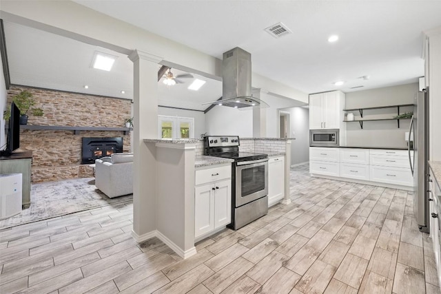 510 Heather Dr, Round Rock, TX 78664 - kitchen with appliances with stainless steel finishes, island exhaust hood, open shelves, light wood-style floors, and a ceiling fan