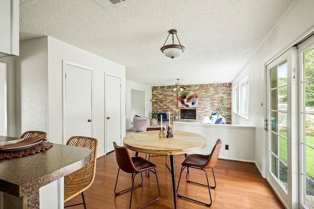 4009 Cordova Dr, Austin, TX 78759 - dining space with a fireplace, light wood-style flooring, and a textured ceiling