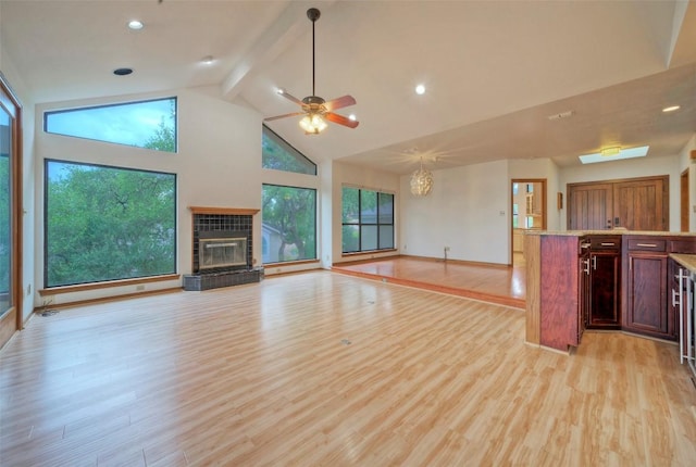 6605 Ladera Norte, Austin, TX 78731 - unfurnished living room featuring a tiled fireplace, beam ceiling, high vaulted ceiling, light wood finished floors, and plenty of natural light