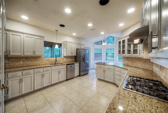 6605 Ladera Norte, Austin, TX 78731 - kitchen with stainless steel appliances, wall chimney range hood, decorative backsplash, light stone countertops, and pendant lighting