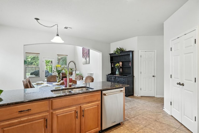 1802 Misty Ridge Dr, Leander, TX 78641 - kitchen featuring dishwasher, arched walkways, dark stone countertops, brown cabinetry, and hanging light fixtures
