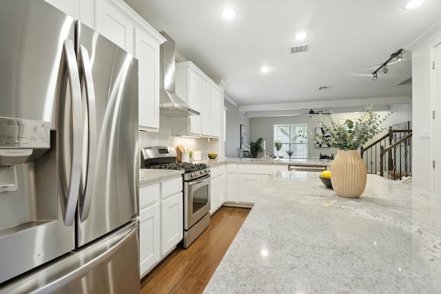 6116 Whipple Way, Austin, TX 78745 - kitchen with appliances with stainless steel finishes, wall chimney range hood, ceiling fan, white cabinetry, and light stone countertops