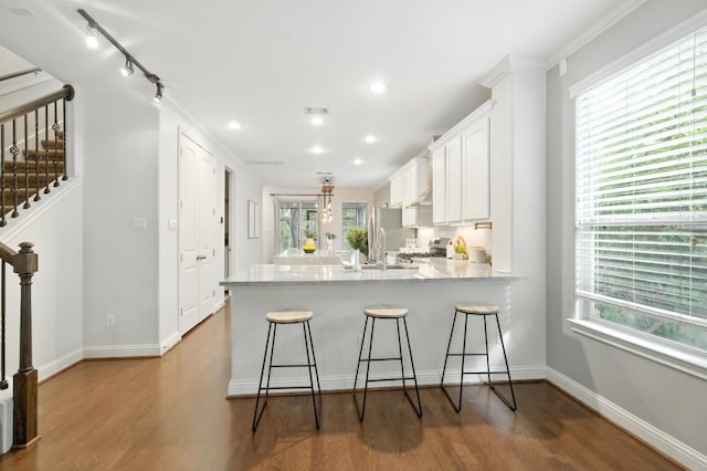 6116 Whipple Way, Austin, TX 78745 - kitchen with a peninsula, white cabinets, plenty of natural light, wood finished floors, and recessed lighting