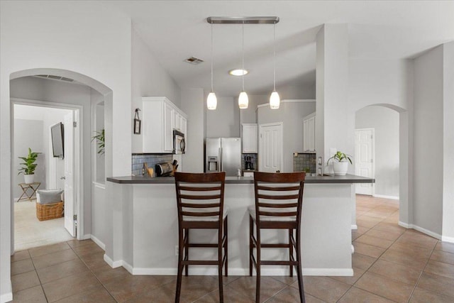 9012 Meacham Way, Austin, TX 78749 - kitchen with stainless steel appliances, arched walkways, dark countertops, tile patterned floors, and a peninsula