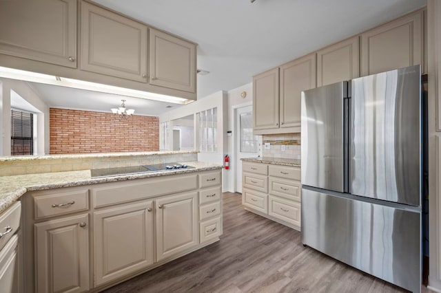 11705 Oak Trl, Austin, TX 78753 - kitchen with freestanding refrigerator, light wood finished floors, a chandelier, cream cabinetry, and brick wall