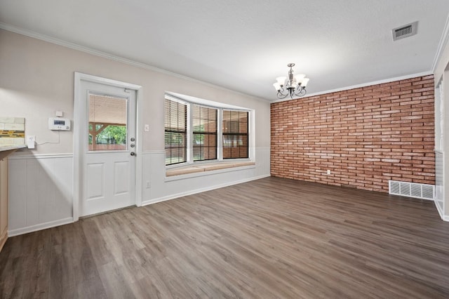 11705 Oak Trl, Austin, TX 78753 - unfurnished dining area featuring a chandelier, wood finished floors, brick wall, wainscoting, and ornamental molding