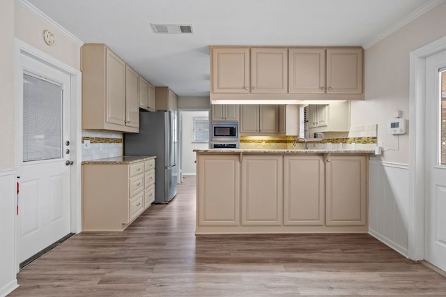11705 Oak Trl, Austin, TX 78753 - kitchen with stainless steel appliances, cream cabinets, a peninsula, light wood-style flooring, and decorative backsplash