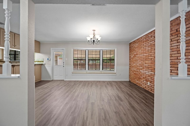 11705 Oak Trl, Austin, TX 78753 - unfurnished dining area with wood finished floors, brick wall, wainscoting, a chandelier, and crown molding