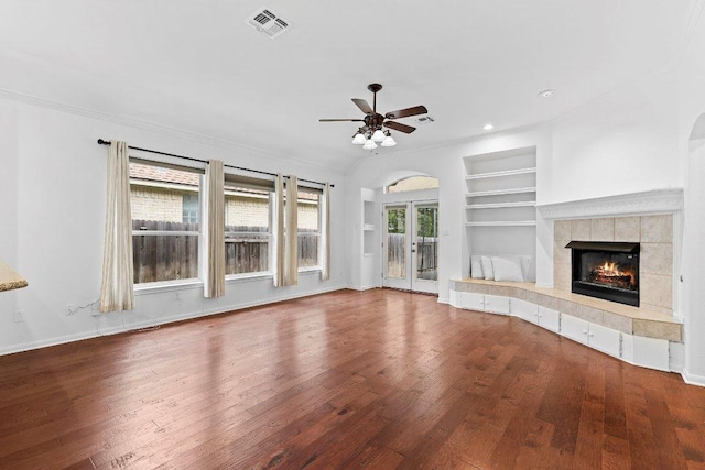 13121 Armaga Springs Rd, Austin, TX 78727 - unfurnished living room with built in features, wood finished floors, ceiling fan, a fireplace, and arched walkways