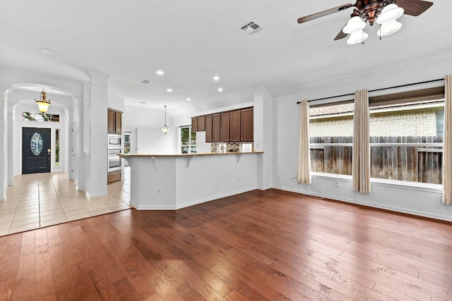 13121 Armaga Springs Rd, Austin, TX 78727 - unfurnished living room featuring ornate columns, ceiling fan, recessed lighting, wood-type flooring, and crown molding