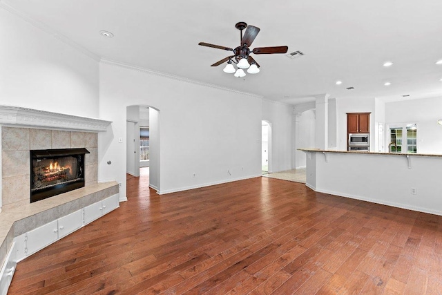 13121 Armaga Springs Rd, Austin, TX 78727 - unfurnished living room with a ceiling fan, a tile fireplace, wood finished floors, crown molding, and recessed lighting