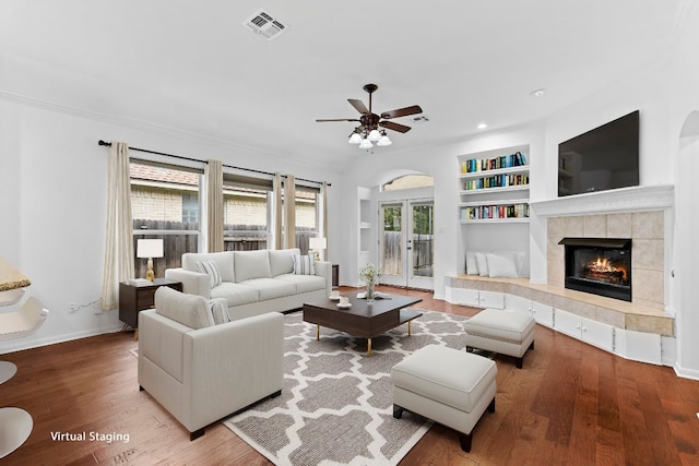 13121 Armaga Springs Rd, Austin, TX 78727 - living area with built in features, ceiling fan, wood finished floors, a tiled fireplace, and crown molding