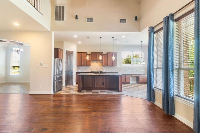 2713 Windy Vane Dr, Pflugerville, TX 78660 - kitchen with stainless steel refrigerator with ice dispenser, a towering ceiling, light wood-style floors, backsplash, and a chandelier