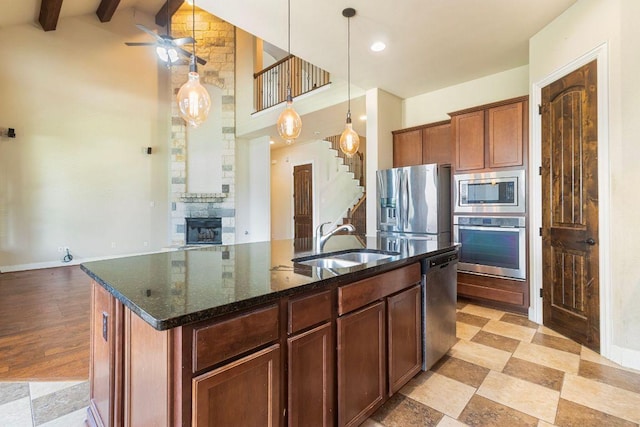 2713 Windy Vane Dr, Pflugerville, TX 78660 - kitchen with stainless steel appliances, ceiling fan, dark stone countertops, a center island with sink, and hanging light fixtures