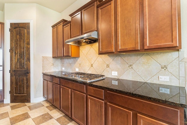 2713 Windy Vane Dr, Pflugerville, TX 78660 - kitchen featuring under cabinet range hood, stainless steel gas stovetop, dark stone countertops, and decorative backsplash