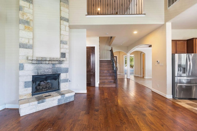 2713 Windy Vane Dr, Pflugerville, TX 78660 - unfurnished living room featuring wood finished floors, arched walkways, a fireplace, stairway, and a high ceiling