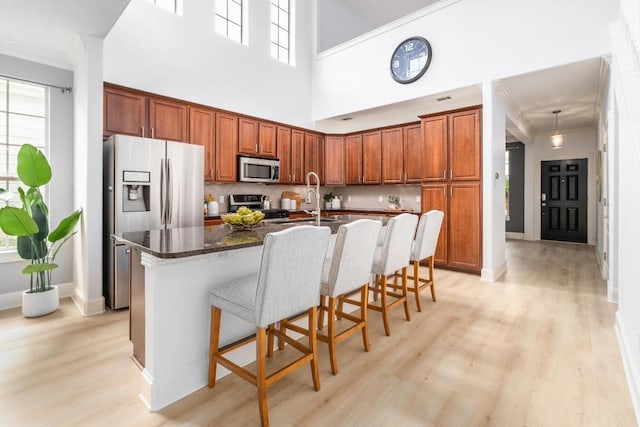 6715 Windrift Way Unit 29, Austin, TX 78745 - kitchen with stainless steel appliances, light wood-type flooring, a kitchen bar, tasteful backsplash, and an island with sink