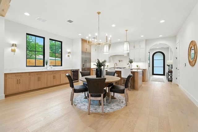 2007 Pasadena Dr, Austin, TX 78757 - dining space with beverage cooler, light wood finished floors, arched walkways, recessed lighting, and a chandelier