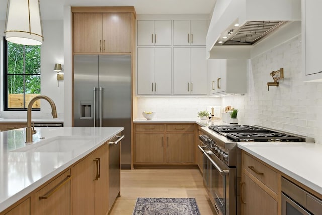 2007 Pasadena Dr, Austin, TX 78757 - kitchen featuring appliances with stainless steel finishes, range hood, light countertops, light wood-type flooring, and backsplash