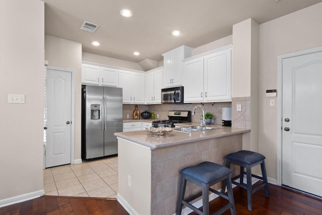 11000 Anderson Mill Rd Unit 52, Austin, TX 78750 - kitchen featuring stainless steel appliances, white cabinetry, a peninsula, a kitchen bar, and tasteful backsplash