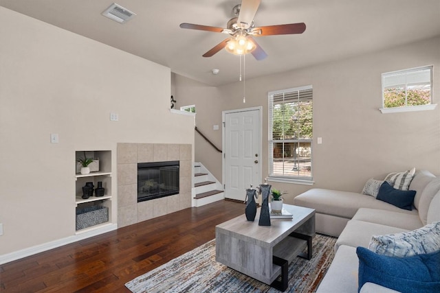 11000 Anderson Mill Rd Unit 52, Austin, TX 78750 - living area featuring dark wood-type flooring, ceiling fan, a tile fireplace, stairs, and built in features