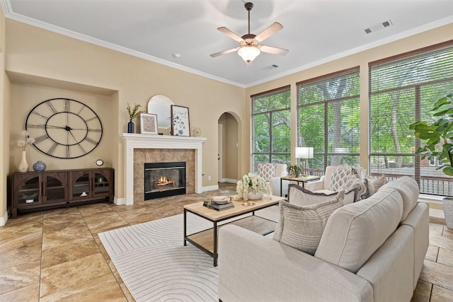 1343 River Forest Dr, Round Rock, TX 78665 - living room with healthy amount of natural light, ceiling fan, ornamental molding, arched walkways, and a tiled fireplace