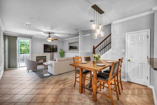 8518 Cahill Dr Unit 23, Austin, TX 78729 - dining space featuring ornamental molding, a ceiling fan, stairway, a tiled fireplace, and light tile patterned floors