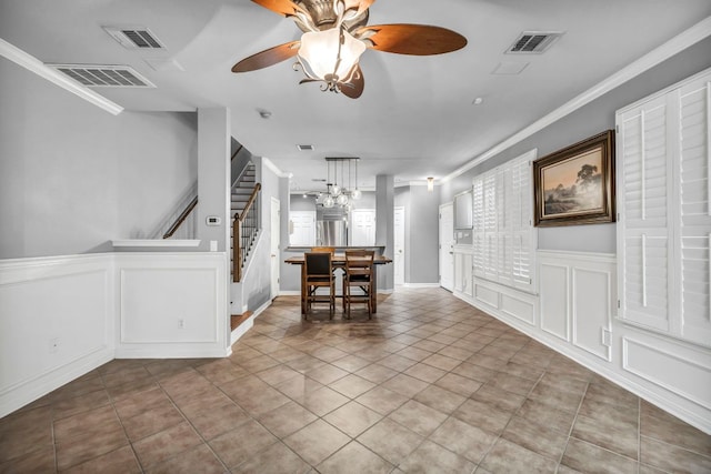 8518 Cahill Dr Unit 23, Austin, TX 78729 - dining space featuring stairs, a decorative wall, tile patterned flooring, a ceiling fan, and crown molding