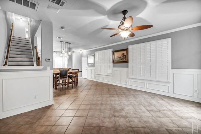 8518 Cahill Dr Unit 23, Austin, TX 78729 - living area featuring a decorative wall, ceiling fan, crown molding, stairway, and tile patterned floors