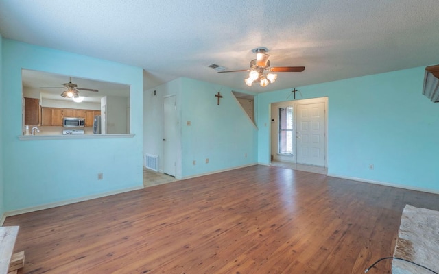 5605 China Berry Rd, Austin, TX 78744 - unfurnished living room featuring ceiling fan, light wood-style flooring, and a textured ceiling