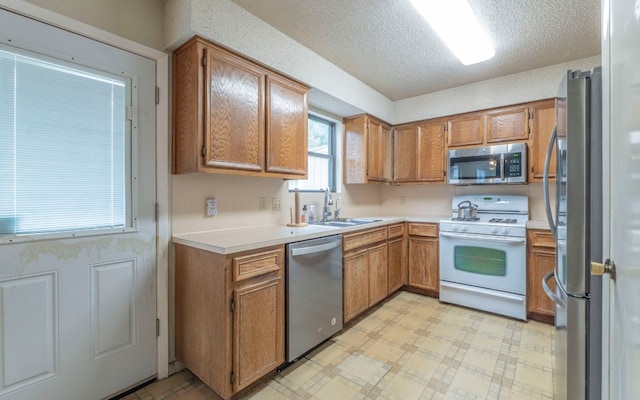 5605 China Berry Rd, Austin, TX 78744 - kitchen featuring stainless steel appliances, light floors, light countertops, brown cabinetry, and a textured ceiling