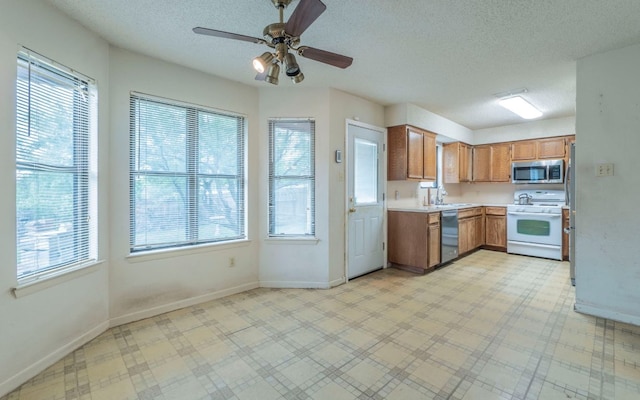 5605 China Berry Rd, Austin, TX 78744 - kitchen featuring stainless steel appliances, healthy amount of natural light, light countertops, a textured ceiling, and a ceiling fan