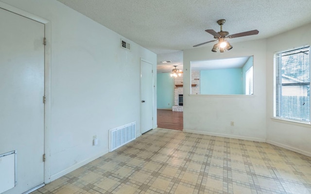 5605 China Berry Rd, Austin, TX 78744 - unfurnished room featuring a ceiling fan, a fireplace, and a textured ceiling