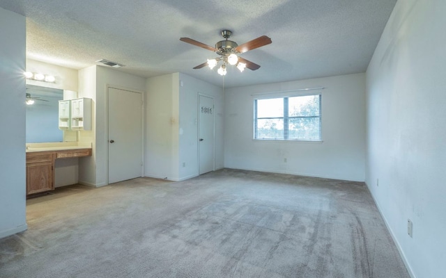 5605 China Berry Rd, Austin, TX 78744 - unfurnished bedroom featuring built in study area, light colored carpet, a textured ceiling, connected bathroom, and a ceiling fan