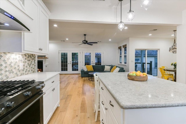3009 Lawrence Dr, Austin, TX 78734 - kitchen featuring black range with gas stovetop, exhaust hood, french doors, decorative backsplash, and white cabinets