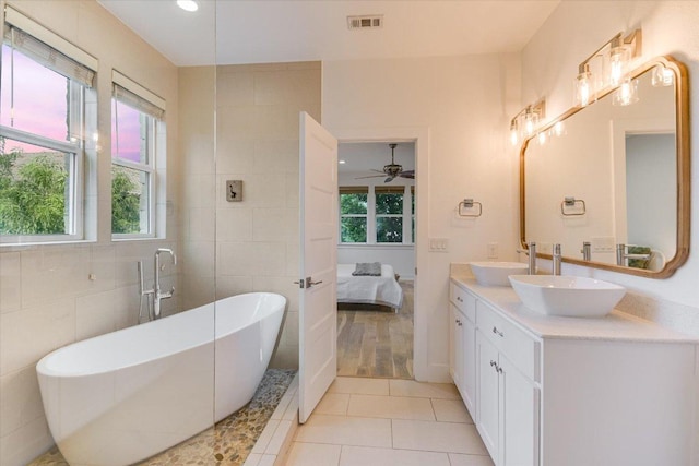 3009 Lawrence Dr, Austin, TX 78734 - ensuite bathroom featuring double vanity, a soaking tub, healthy amount of natural light, tile patterned floors, and tile walls