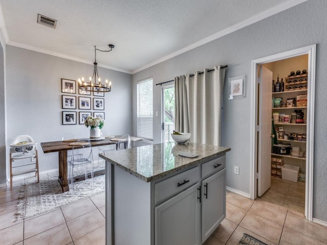 13320 Gilwell Dr, Del Valle, TX 78617 - kitchen featuring crown molding, light stone counters, light tile patterned flooring, a chandelier, and a center island