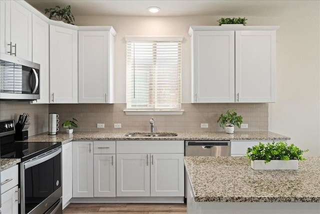 212 Gunther Way, Taylor, TX 76574 - kitchen featuring appliances with stainless steel finishes, white cabinets, tasteful backsplash, and light stone counters