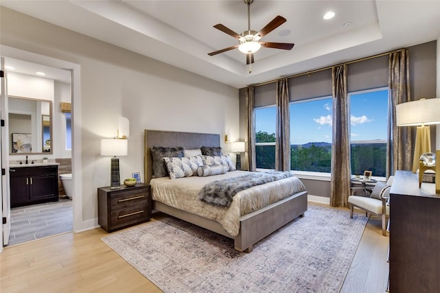 19617 Serenity Ln, Lago Vista, TX 78645 - bedroom featuring a tray ceiling, light wood-style floors, recessed lighting, ensuite bath, and ceiling fan