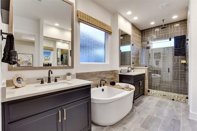 19617 Serenity Ln, Lago Vista, TX 78645 - bathroom with a shower stall, two vanities, a freestanding bath, recessed lighting, and tile walls