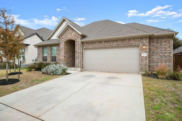 1921 Sauterne Dr, Leander, TX 78641 - view of front facade featuring a garage, driveway, brick siding, and roof with shingles
