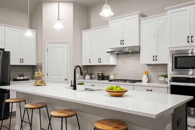 1921 Sauterne Dr, Leander, TX 78641 - kitchen featuring appliances with stainless steel finishes, a breakfast bar, tasteful backsplash, white cabinetry, and hanging light fixtures