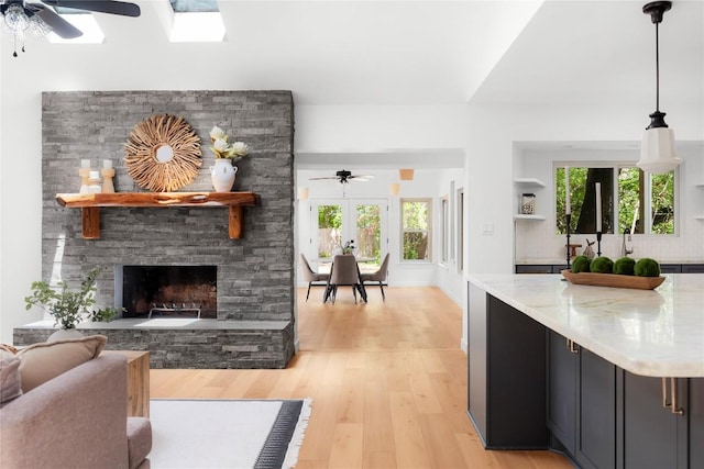 9309 Cedar Forest Dr, Austin, TX 78750 - living area featuring ceiling fan, light wood-style floors, a stone fireplace, and healthy amount of natural light