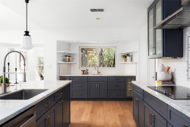 9309 Cedar Forest Dr, Austin, TX 78750 - kitchen with black electric stovetop, open shelves, stainless steel dishwasher, tasteful backsplash, and light wood-style floors