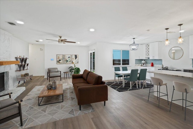 3803 Alexandria Dr, Austin, TX 78749 - living area featuring wood finished floors, recessed lighting, a stone fireplace, a ceiling fan, and a chandelier