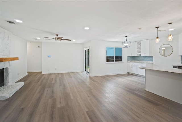 3803 Alexandria Dr, Austin, TX 78749 - unfurnished living room with a stone fireplace, a chandelier, recessed lighting, light wood-style floors, and ceiling fan