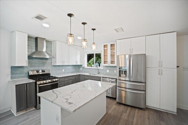 3803 Alexandria Dr, Austin, TX 78749 - kitchen with stainless steel appliances, wall chimney exhaust hood, wood finished floors, gray cabinets, and decorative backsplash