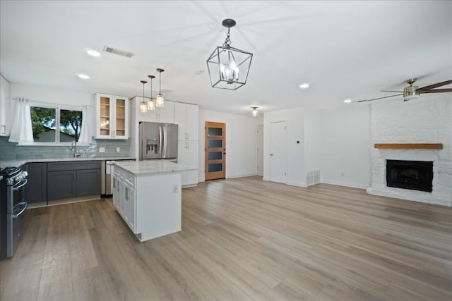 3803 Alexandria Dr, Austin, TX 78749 - kitchen featuring appliances with stainless steel finishes, a kitchen island, tasteful backsplash, open floor plan, and light wood-style floors