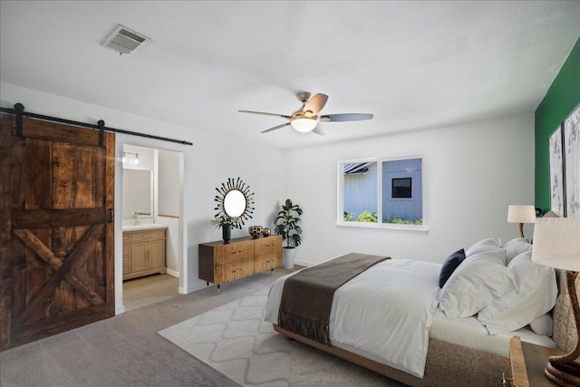 3803 Alexandria Dr, Austin, TX 78749 - bedroom with a barn door, light colored carpet, ensuite bath, and ceiling fan