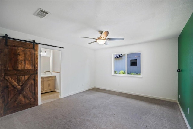 3803 Alexandria Dr, Austin, TX 78749 - unfurnished bedroom with a barn door, carpet floors, a ceiling fan, and connected bathroom